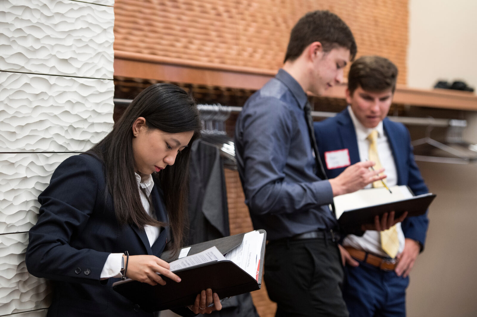 Three students regroup and discuss tactics as they take a break from a networking event.